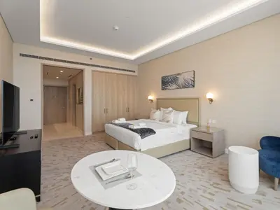 a hotel room with a bed and a table and a tv at Sunset Bliss Elegant Palm Island Studio in Dubai