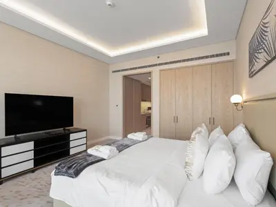 a bedroom with a white bed and a flat screen tv at Sunset Bliss Elegant Palm Island Studio in Dubai