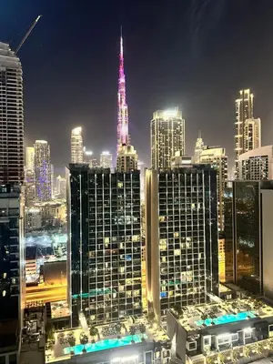 a city skyline at night with a lit up tower at Modern 2BR I DAMAC Reva Residences I Canal Views in Dubai
