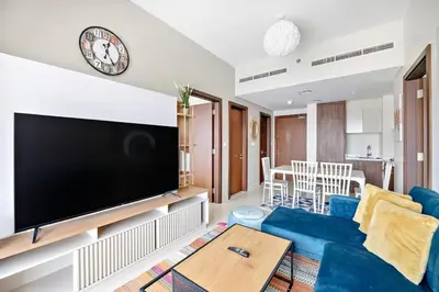 a living room with a blue couch and a flat screen tv at Modern 2BR I DAMAC Reva Residences I Canal Views in Dubai