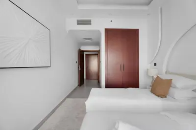 a white bedroom with a white bed and a wooden door at GuestReady - 3BR | Luxury High-Rise Escape in Dubai