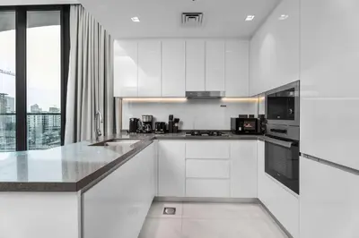 a kitchen with white cabinets and a large window at Luxury 1BR with Private Pool & Balcony in Dubai