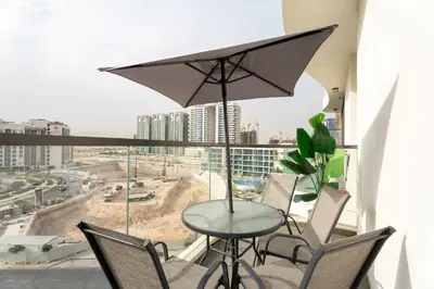 a table with chairs and an umbrella on a balcony at Luxury 1BR with Private Pool & Balcony in Dubai
