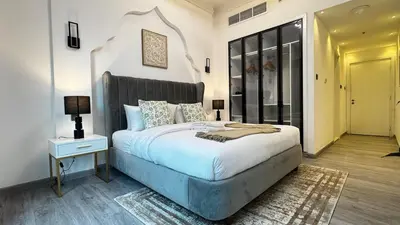 a bedroom with a large white bed with a nightstand and a lamp at 4BDR Duplex Apartment 8 Guests in Dubai