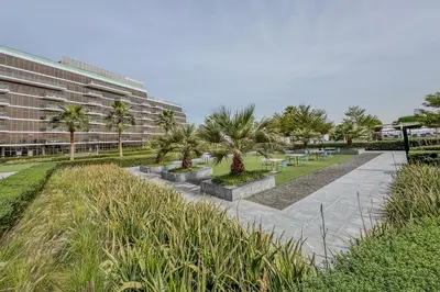 a park with palm trees and a building at Stunning 2 Bedroom in Palm with private beach in Dubai