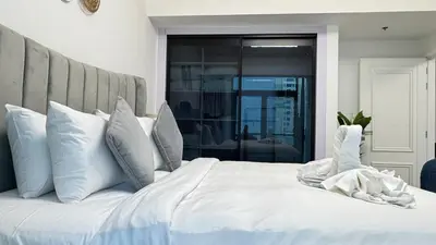 a white bed with white pillows and a headboard at 1 Bedroom centrally located with large balcony in Dubai