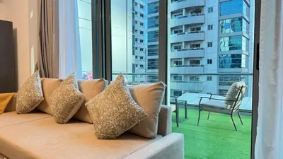 a couch with pillows sitting in front of a window at 1 Bedroom centrally located with large balcony in Dubai