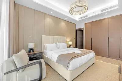 a bedroom with a large bed and a chair at Nobles Tower- Luxe with Skies-High 1BR Lifestyle in Dubai
