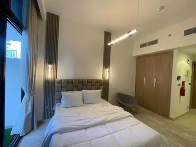 a bedroom with a large white bed and a chair at Quiet Studio in Azizi 18-Ideal for Work & Leisure in Dubai