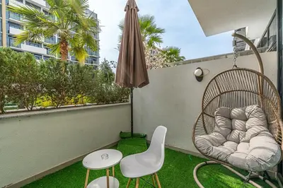 a balcony with a rattan chair and a swing at Chic Studio at Azizi Riviera Near Downtown Dubai in Dubai