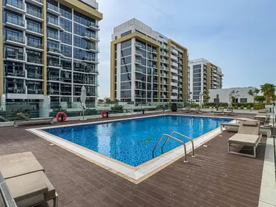 a large swimming pool with two tall buildings at Chic Studio at Azizi Riviera Near Downtown Dubai in Dubai