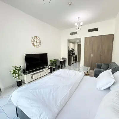 a white bedroom with a large bed and a flat screen tv at An elegant sanctuary in Dubai