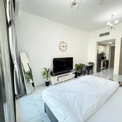 a white bedroom with a bed and a tv at An elegant sanctuary in Dubai