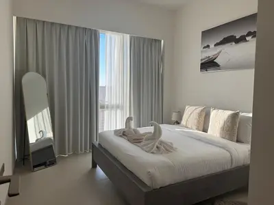a white bedroom with a large bed and a large window at Harmonizing apartment 1BR with a balcony in Grande in Dubai