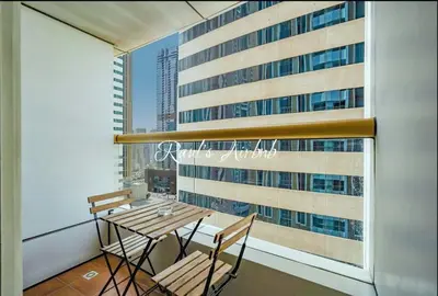 a balcony with a table and chairs and a large window at Lovely beach life 1 bed apartment in Dubai Marina in Dubai