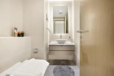 a white bathroom with a sink and a mirror at Luxe 1BR with Balcony & Canal View in Dubai