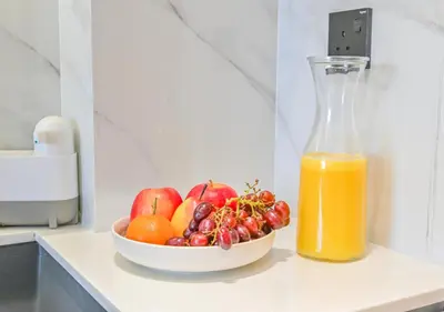 a bowl of fruit next to a bottle of orange juice at Stylish JVC Studio Hotel-Style Comfort in Dubai