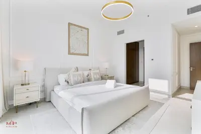 a white bedroom with a large white bed and a table at Canal-Side Living Elegant 2BR at Canal Front in Dubai