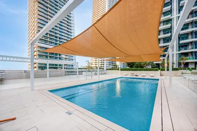 a pool with a large umbrella and some buildings at Beachfront stay at Beach Mansion with Private Beach in Dubai