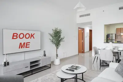 a living room with a book me sign on the wall at StayShort - Modern JVC 1 bed Sleeps 4 with Swimming Pool in Dubai
