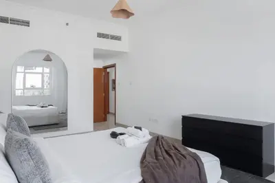 a bedroom with two white beds and a mirror at StayShort - Modern JVC 1 bed Sleeps 4 with Swimming Pool in Dubai