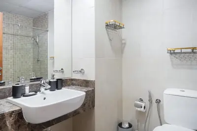 a white bathroom with a sink and a toilet at StayShort - Modern JVC 1 bed Sleeps 4 with Swimming Pool in Dubai