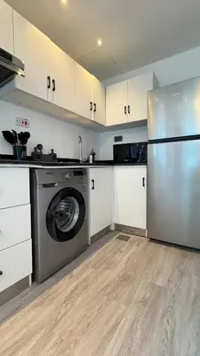 a kitchen with a washing machine and white cabinets at 1BDR Centrally Located Fully Equipped Kitchen in Dubai