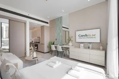 a living room with white furniture and a kitchen at Boutique Studio at Binghatti Aurora by Czechin in Dubai