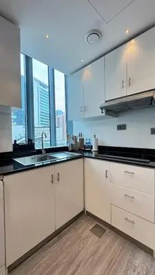 a kitchen with white cabinets and large windows at 1 Bedroom Centrally located near the Metro in Dubai
