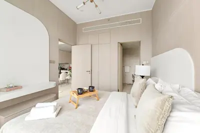 a bedroom with a white bed and a table at VayK - Bright Modern Apartment in JVC - 1BR Gem in Dubai
