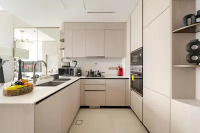 a kitchen with white cabinets and a bowl of fruit on the counter at VayK - Bright Modern Apartment in JVC - 1BR Gem in Dubai