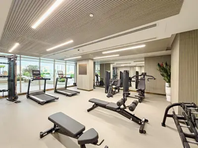 a gym with several treadmills and elliptical machines at VayK - Bright Modern Apartment in JVC - 1BR Gem in Dubai