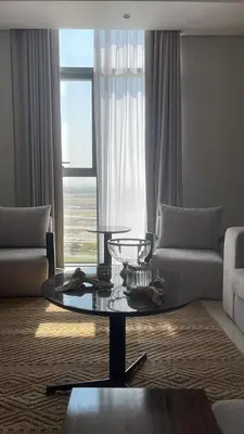 a living room with a glass coffee table in front of a window at Stylish 2BR in Business Bay with all essentials in Dubai