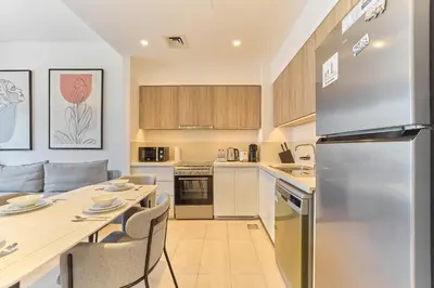 a kitchen with a refrigerator and a table with chairs at Bright 1BR in Executive Residences 2, Dubai Hills in Dubai