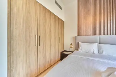 a bedroom with a large bed and wooden cabinets at Bright 1BR in Executive Residences 2, Dubai Hills in Dubai