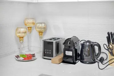 a kitchen counter with a toaster and a tea kettle and glasses at Modern 2BDR Stay-Near Metro-Al Furjan in Dubai