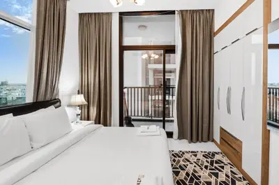 a bedroom with a white bed and a balcony at Modern 2BDR Stay-Near Metro-Al Furjan in Dubai