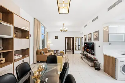 a living room with a table and chairs and a kitchen at Modern 2BDR Stay-Near Metro-Al Furjan in Dubai