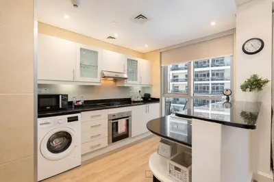 a kitchen with white cabinets and a washer and dryer at Modern 1BHK Jewels Tower, Dubai Marina by Czechin in Dubai
