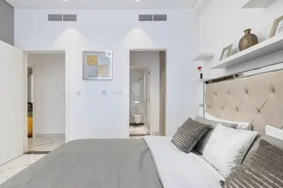 a bedroom with a large bed with white walls at VayK - Extra-Large 2BR in Dubai Hills Close to Mall & Park in Dubai