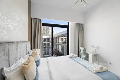 a hotel room with a bed and a large window at VayK - Contemporary 1BR in a New JVC Community in Dubai