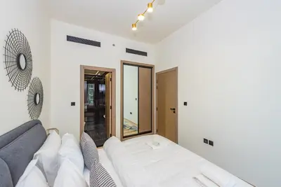 a white living room with a couch and a mirror at VayK - Chic 1BR Urban Getaway in Dubai