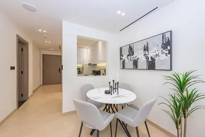 a white dining room with a white table and chairs at VayK - Chic 1BR Urban Getaway in Dubai