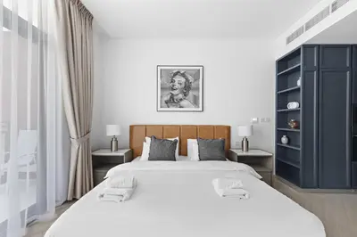 a white bedroom with a large bed and two tables at VayK - Ideal Studio in Sobha Hartland in Dubai