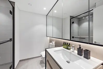 a white bathroom with a sink and a mirror at VayK - Ideal Studio in Sobha Hartland in Dubai