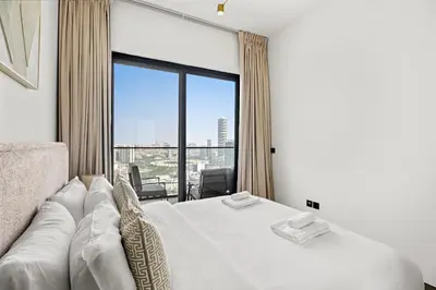 a bedroom with a white bed and a large window at VayK - Comfortable 1BR in JVC in Dubai