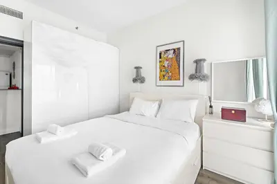 a white bedroom with a large white bed with two towels at VayK - Modern 1BR Near Metro in Dubai Marina in Dubai