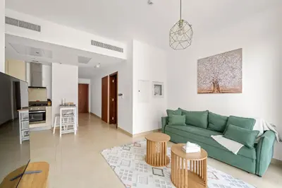 a living room with a green couch and a kitchen at VayK - Lovely 1BR in Central Dubai Marina in Dubai