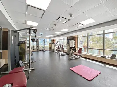 a gym with cardio equipment and red chairs and windows at VayK - Inviting 1BR in Dubai Marina with Stunning Views in Dubai