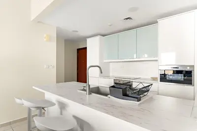 a white kitchen with a counter and a sink at VayK - Light-Filled and Spacious 1BR in JBR in Dubai
